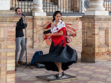 Seville, İspanya - 10 Ocak 2021: Sevilla Plaza de Espana 'da dans eden renkli elbiseli tutkulu flamenko dansçısı kadın