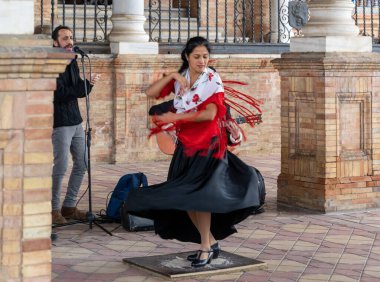 Seville, Spain - 10 January, 2021: passionate flamenco dancer woman in colorful clothes dancing at the Plaza de Espana in Seville clipart