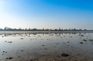 Dalgaların çekildiği sularda, arka planda kıyıları olan bir sürü dev gelgit havuzu var.