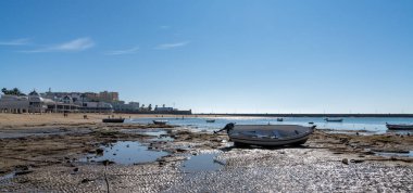 Cadiz, İspanya - 16 Ocak 2021: Cadiz 'deki La Caleta plajının alçak gelgitte karaya vurmuş ahşap balıkçı tekneleriyle manzarası