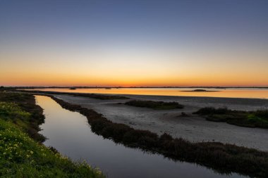 Sulak alanlar ve kanallar üzerinde renkli bir gökyüzü olan güzel bir gece doğumu.