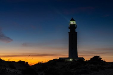 Cape Trafalgar deniz fenerinin gün batımından sonra renkli akşam gökyüzü manzarası