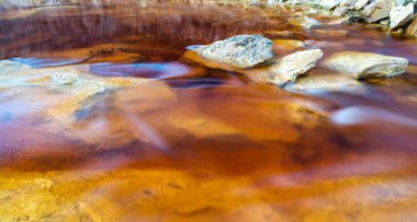 Rio Tinto madencilik bölgesinde demir cevheri ve bakır cevherleriyle turuncu kırmızı nehri kapatın.