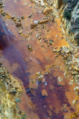 Yüzeysel sularda mineral ve metal birikintileri olan terk edilmiş bir maden alanındaki nehir yatağının soyut bir görüntüsü.