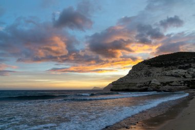 İspanya 'da Costa del Sol' da güzel bir okyanus gün batımı. Sahilde ve arka planda kayalıklar var.