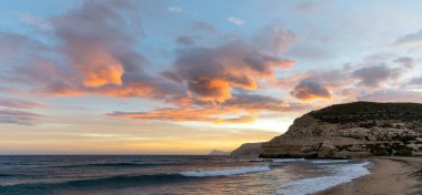 İspanya 'da Costa del Sol' da güzel bir okyanus batımı sahili ve arka planda kayalıkları olan.