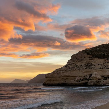 İspanya 'da Costa del Sol' da güzel bir okyanus gün batımı. Sahilde ve arka planda kayalıklar var.