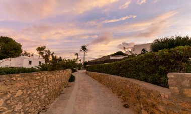 Agua Amarga, İspanya - 10 Şubat 2021: Gün batımında Endülüs 'ün Agua Amarga kentindeki Costa del Sol' da huzurlu tatil evlerine giden yol