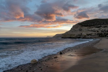 İspanya 'da Costa del Sol' da güzel bir okyanus gün batımı. Sahilde ve arka planda kayalıklar var.