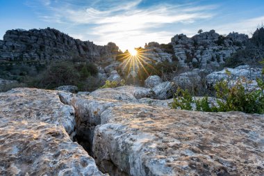 Endülüs 'teki El Torcal Doğa Rezervi' nde bir güneş yıldızıyla akşam ışıklarıyla birlikte tuhaf karst kaya oluşumlarıyla manzara.