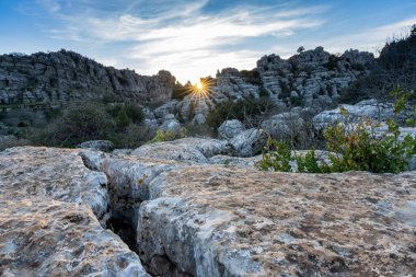 Endülüs 'teki El Torcal Doğa Rezervi' nde bir güneş yıldızıyla akşam ışıklarıyla birlikte tuhaf karst kaya oluşumlarıyla manzara.