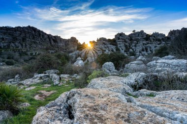 Endülüs 'teki El Torcal Doğa Rezervi' nde bir güneş yıldızıyla akşam ışıklarıyla birlikte tuhaf karst kaya oluşumlarıyla manzara.