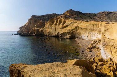 Akdeniz 'deki sakin ve sakin okyanus sularının ardında sarı kumtaşı kayalıkları var.