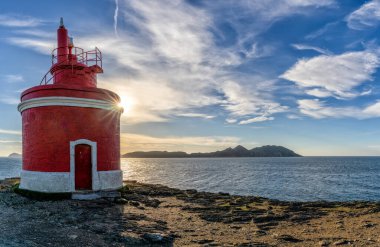 Punta Robaleira deniz fenerinin arkasındaki altın güneş Galiçya ve Cies Adaları 'nın arkasında.