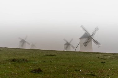 Çok sisli bir sabahta La Mancha 'daki Campo de Criptana yel değirmenlerinin manzarası.