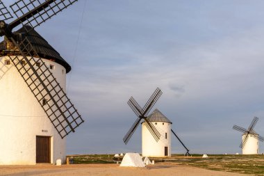 Campo de Criptana kasabasının yukarısındaki La Mancha 'nın tarihi beyaz yel değirmenlerinin sıcak akşam ışığında manzarası.