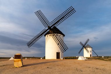 Campo de Criptana kasabasının yukarısındaki La Mancha 'nın tarihi beyaz yel değirmenlerinin sıcak akşam ışığında manzarası.
