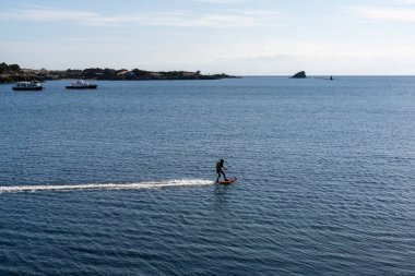 Cadaques, Spain - 13 March, 2021: man riding a motorized surfboard in the Mediterranean Sea near Cadaques clipart