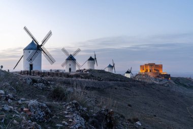İspanya 'nın orta kesimindeki La Mancha' daki Consuegra kalesinin ve yel değirmenlerinin günbatımının manzarası.