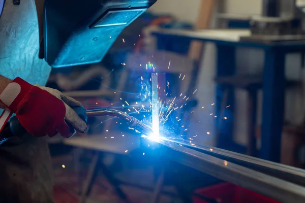 A metal worker welding and fabricating a metal frame for a garden patio