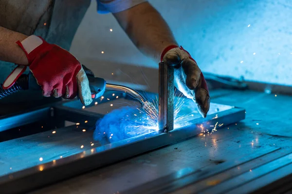 A metal worker welding and fabricating a metal frame for a garden patio