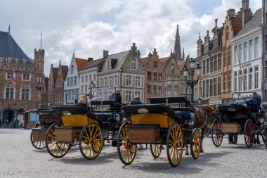 Bruges, Belçika - 12 Mayıs 2021: park edilmiş atlar ve arabalar insanların tarihi şehir merkezi Bruges 'deki Pazar Meydanı' nda gezinti yapmalarını bekliyor.