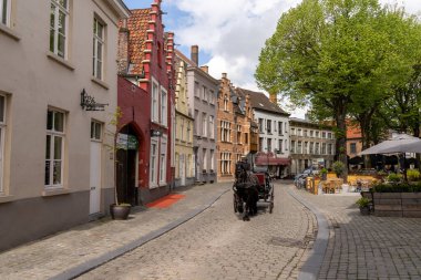 Bruges, Belçika - 12 Mayıs 2021: turistler tarihi eski Brugge kasabasında cennet gibi bir at ve at arabası şehir turunun keyfini çıkarıyorlar.