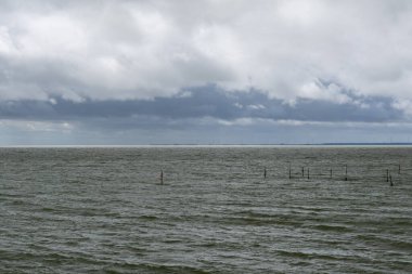 Kuzey Hollanda 'daki tipik Wadden Denizi manzarası Den Oever yakınlarında rüzgarlı bir okyanus ve anlamlı bulutlu bir gökyüzü