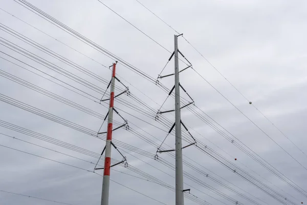 曇りの空の下で背の高い格子が交差し 高電圧電源ラインの近くのビュー — ストック写真