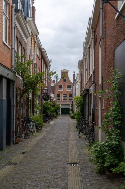 Haarlem, Hollanda - 21 Mayıs 2021: Haarlem 'in tarihi şehir merkezinde tuğla binalar bulunan dar kaldırım taşı caddesi