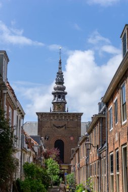 Haarlem, Hollanda - 21 Mayıs 2021: Dar bir şehir caddesi ve Haarlem şehir merkezindeki Wilhelminakerk kilisesi manzarası