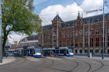 Amsterdam, Hollanda - 19 Mayıs 2021: Amsterdam şehir merkezindeki ana istasyonun dışında tren istasyonları ve bekleyen insanlar