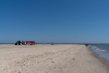 Skagen, Danimarka - 4 Haziran 2021: Danimarka 'nın kuzey ucuna turistleri getiren traktör römorku mavi gökyüzünün altında park halinde.