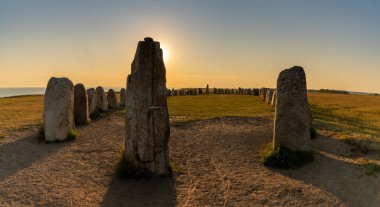 İsveç 'in güney kıyısında gün batımında batan tarih öncesi Ales Stenar gemisinin manzara görüntüsü.