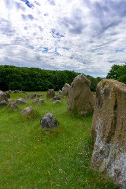 Lindholm Hills 'teki Viking mezarlığının dikey görüntüsü. Beyaz bulutlu mavi bir gökyüzünün altında.