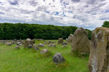 Lindholm Hills 'teki beyaz bulutlu mavi bir gökyüzünün altındaki Viking mezarlığının manzarası.