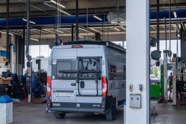 Odense, Danimarka - 10 Haziran 2021: Gri karavan modern bir garajda motor tamiri için.