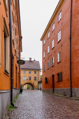Uppsala, İsveç - 25 Haziran 2021: Uppsala 'nın tarihi şehir merkezinde kırmızı ve turuncu taş binalı boş kaldırım taşı caddesi