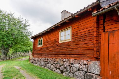 Gamla Uppsala, İsveç - 24 Haziran 2021: Güzel bir yaz gününde yeşil çayırlı İsveç kırsalındaki cennet kırmızısı ev