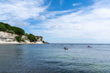 Hojerup, Danimarka - 12 Haziran 2021: Dik beyaz tebeşir taşı uçurumları, ormanı ve kayaları olan güzel bir okyanus manzarası.