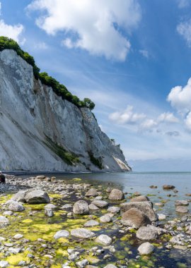 Resmedilmeye değer bir okyanus ve sakin sularla dolu bir sahil ve beyaz kümülüs bulutlarıyla mavi gökyüzünün altında sarp beyaz tebeşir taşı uçurumları.
