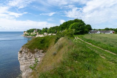 Okyanus kıyısındaki yaban tırtıklı kayalıklar uçurumun kenarında bir kilise ve çiftlik arazisi var.