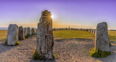 Tarih öncesi Ales Stenar gemisinin günbatımında İsveç 'in güney kıyısında güneşli bir gökyüzünün altında batarken manzarası.