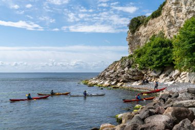 Hojerup, Danimarka - 12 Haziran 2021: Bir grup deniz kayakçısı Stevns Klint kıyısındaki kayalık bir plaja indiler.