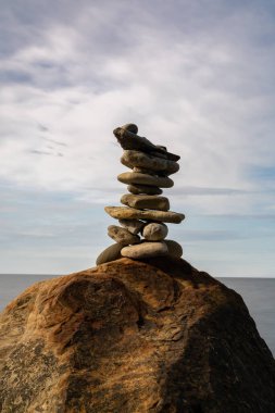Bir kayanın tepesinde meditasyon yapan bir kaya cairn. Arka planda okyanus ve gökyüzü var.