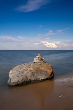 Bir kayanın tepesinde meditasyon yapan bir kaya cairn. Arka planda okyanus ve gökyüzü var.