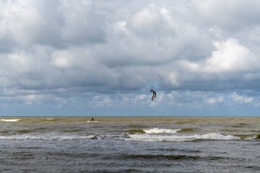 Bir uçurtma sörfçüsü, Pavilosta 'daki Baltık kıyılarında sert bir rüzgarın tadını çıkarır.