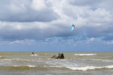Bir uçurtma sörfçüsü, Pavilosta 'daki Baltık kıyılarında sert bir rüzgarın tadını çıkarır.