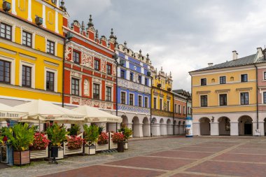 Zamosc, Polonya - 13 Eylül 2021: Eski Zamosc şehir merkezindeki Büyük Pazar Meydanı 'ndaki renkli Rönesans binaları ve sokak restoranları