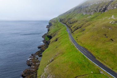 Sandoy Adası 'nın engebeli kıyı şeridi ve Faroe Adaları' ndaki Husavikervegur Otoyolu 'nun insansız hava aracı görüntüsü.